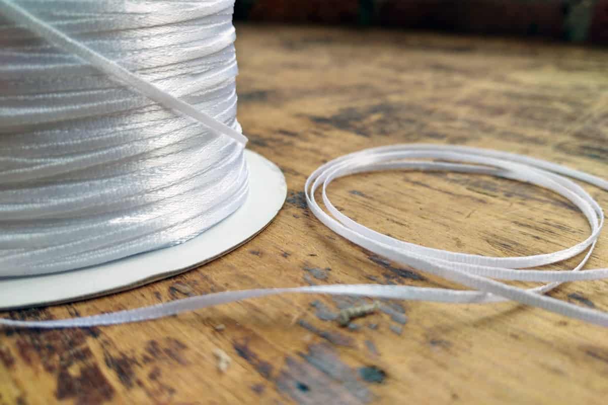 A spool (and a small coiled length) of our new double-faced satin ribbon, in white.