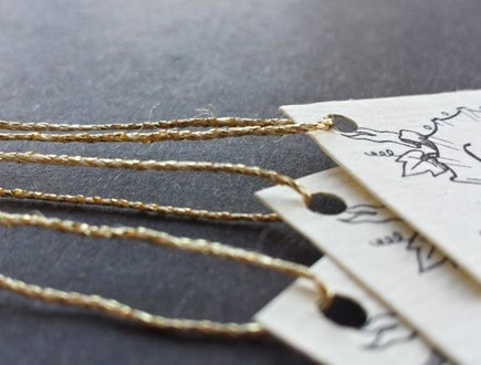 Tags with leaf and ribbon design strung with 3-ply gold lamé.