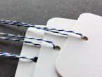 White tags with rounded corners strung with blue bakery twine.