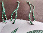 Scalloped-edge tags strung with heavyweight variegated green-white cotton string.