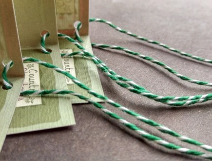 Folded tags strung with heavyweight variegated green-white cotton string.