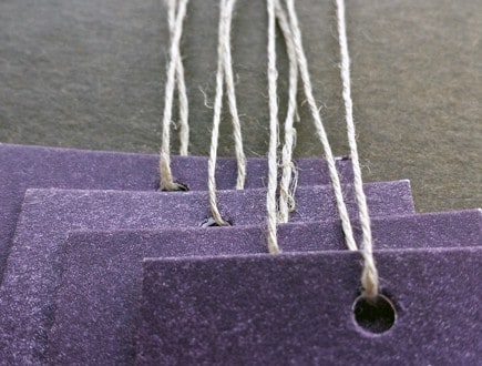 Tags on purple stock strung with our 3-ply hemp.