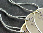 Foil-stamped oval tags strung with our gold-natural metallic yarn.