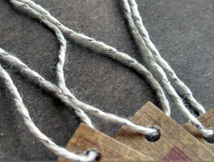 Folded tags with textured paper strung with our silver-white metallic yarn.
