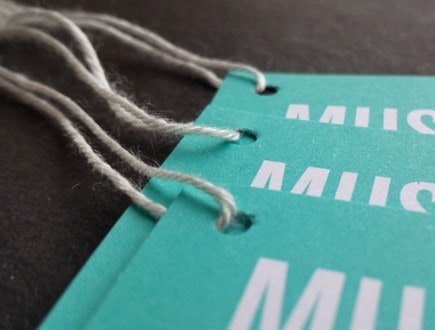Teal museum tags with white copy strung with standard white rayon string.