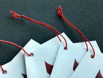 Folded white tags with red logo strung with standard elastic in red.