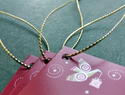Cranberry-red folded tags with star and dove motifs strung with our gold braid.