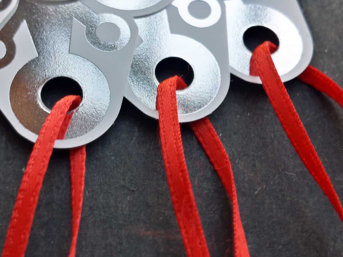 Photograph of elaborate die-cut tags strung with red satin ribbon.