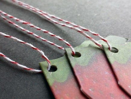 Folded die-cut strawberry-shaped tags strung with red bakery twine.