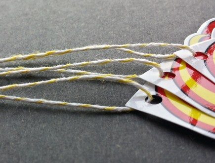 Glossy tag with red and yellow graphics strung with yellow bakery twine.