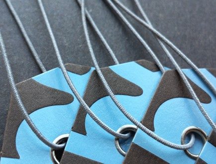 Brown tags with blue copy strung with gray non-fray elastic.