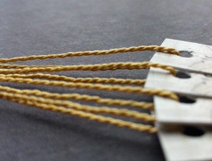 Narrow tags in neutral hue strung with lightweight 1200 gold Pearlray.