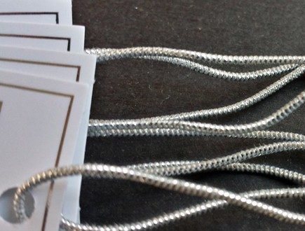 White tags with silver foil border strung with our silver metallic elastic.