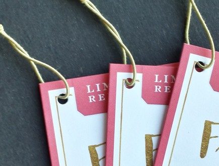 Pink and white tags with gold copy strung with standard elastic in antique gold.