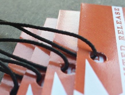 Red ochre tags strung with standard elastic in black.