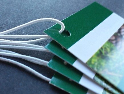 Green and white tags with foliage graphic strung with standard elastic in white.